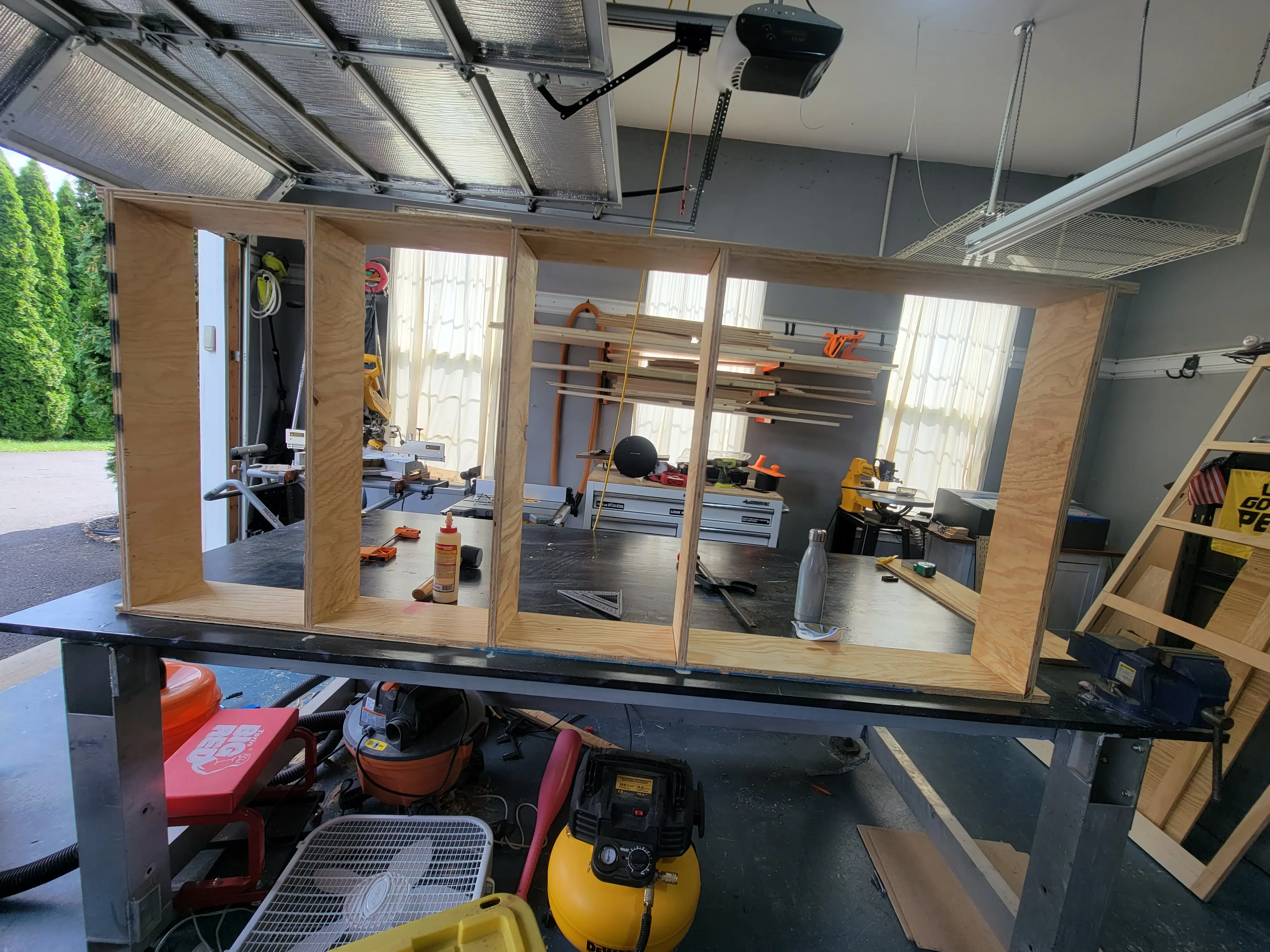 wood face frame in a garage. Garage door is open, face frame is on a workbench. Well lit with a yellow compressor on the floor